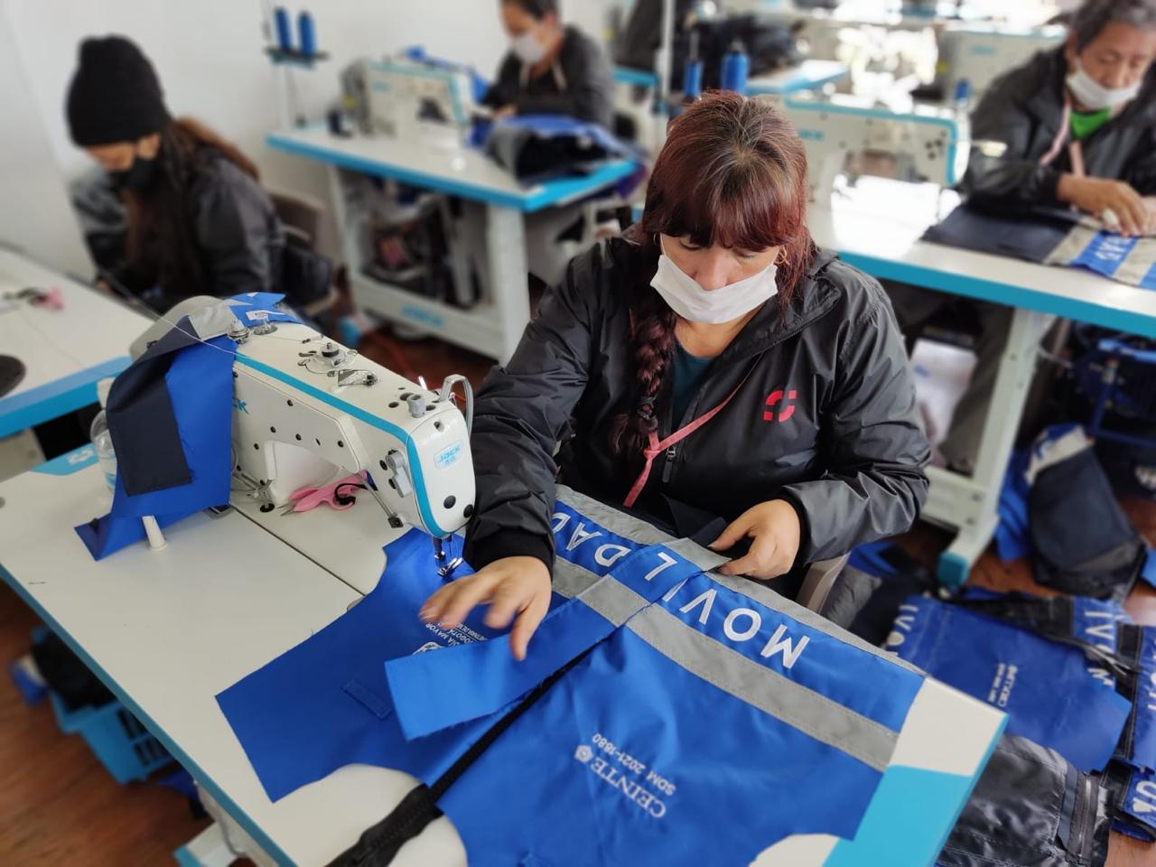 Costurera cosiendo chaqueta con bandas reflectivas